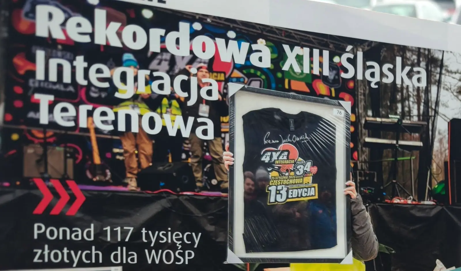Licytacja koszulki 13. edycji z autografem Jurka Owsiaka na scenie finałowej. Nagłówek artykułu: Rekordowa XIII Śląska Integracja Terenowa, ponad 117 tysięcy złotych dla WOŚP
